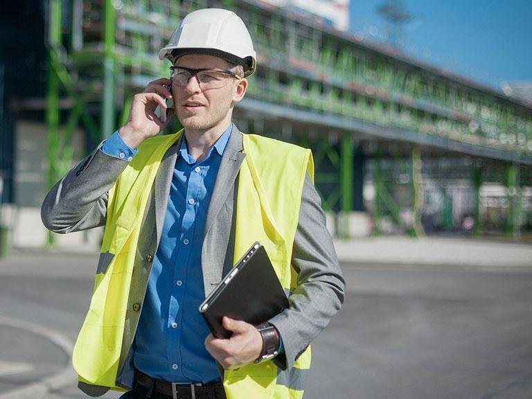 Architekt w białym kasku rozmawia przez telefon